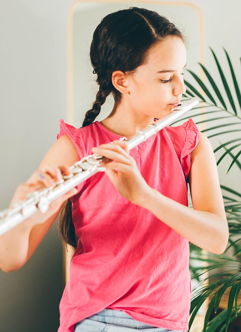 Chica tocando la flauta travesera en casa.